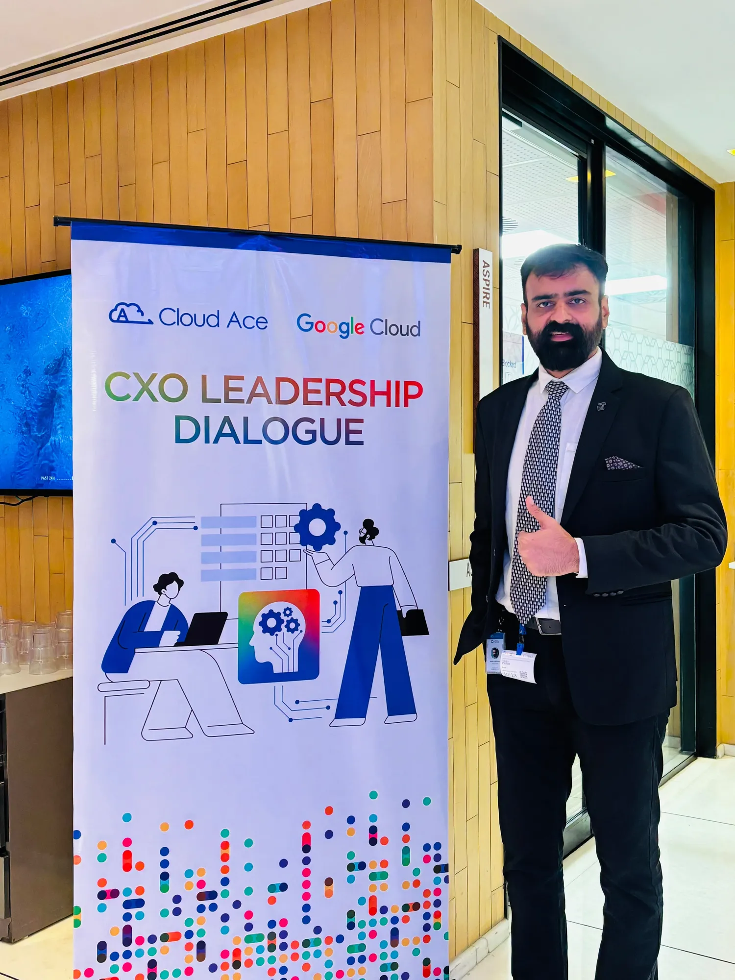 A host in a dark suit giving a thumbs-up beside the CXO Leadership Dialogue banner