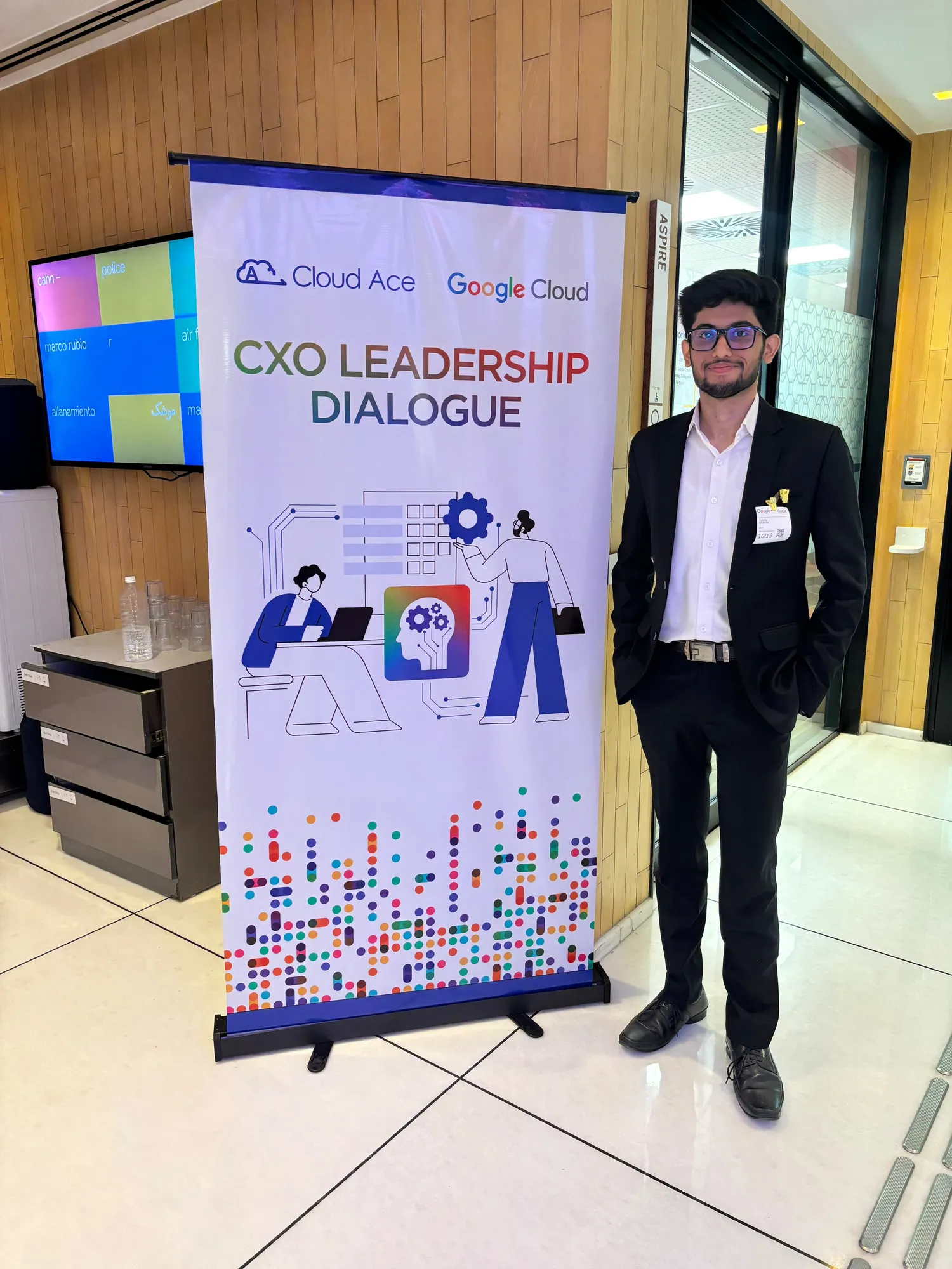 A colleague in a dark suit standing beside the CXO Leadership Dialogue banner